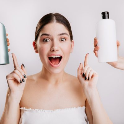 Žena poukazující na dva druhy šamponů
