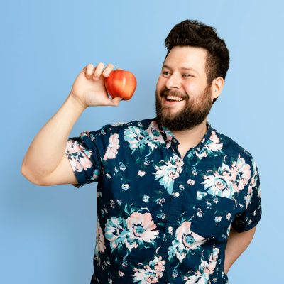 Muž drží v ruce jablko a usmívá se