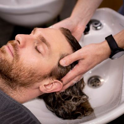 Muž, kterému kadeřník myje vlasy