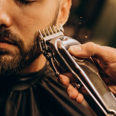 Muž, kterému barber stříhá bradu strojkem