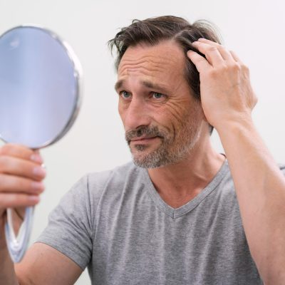 Muž zkoumá své vlasy pohledem do zrcadla