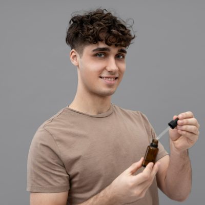 Mladý muž drží v rukou lahvičku s olejem na vlasy
